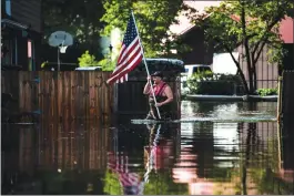  ?? Washington Post photo by Jabin Botsford ?? A man carries a flag to place on his truck as members of a team with the United States Coast Guard perform search and rescue through flood waters in Lumberton, N.C., in the aftermath of Hurricane Florence on Monday.