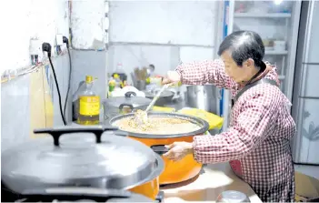  ??  ?? Wen Junhong preparing dog food at a home for rescued animals in Chongqing, southweste­rn China.