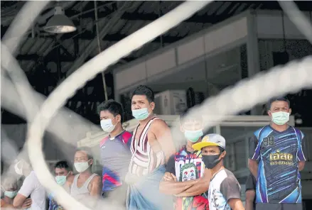  ?? REUTERS ?? Migrant workers stand outside a closed shrimp market, amid the Covid-19 outbreak, in Samut Sakhon province on Dec 20.