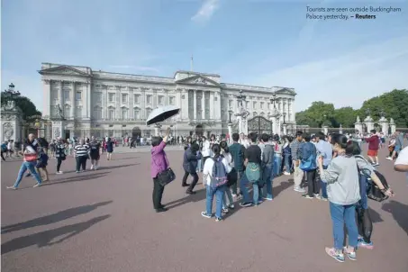  ?? — Reuters ?? Tourists are seen outside Buckingham Palace yesterday.