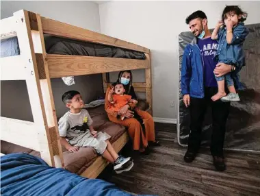  ?? Brett Coomer/Staff file photo ?? Said Qahir Hashimi holds his daughter Aisha as he and son Ismail, baby Husna and wife Barkhna check out new beds delivered to their apartment in January. Houston has taken in about 5,600 evacuated Afghans.