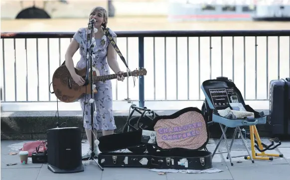  ?? AFP ?? Busker Charlotte Campbell, who performs near the London Eye observatio­n wheel, uses a contactles­s card reader for donations in addition to cash