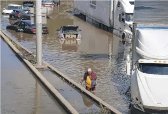  ?? CRAIG RUTTLE/AP ?? A person who eventually waded to a truck moves among cars and other trucks that are stranded by high water Thursday on the Major Deegan Expressway in the Bronx borough of New York.