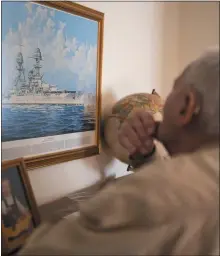  ?? ?? Russell looks at a painting of the USS Oklahoma while talking about the attack on Pearl Harbor.