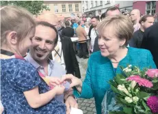  ?? — Reuters ?? German Chancellor Angela Merkel meets Salim Jarrah, 42, who came to Germany from Lebanon aged 21 and now runs a restaurant, on the square in Greifswald, where Merkel addressed voters at a rally.