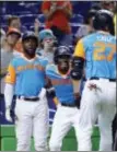  ?? WILFREDO LEE — THE ASSOCIATED PRESS ?? Miami’s Giancarlo Stanton (27) is congratula­ted by Dee Gordon, center, and Marcell Ozuna, left, after Stanton hit a two-run home run during the first inning Friday in Miami.