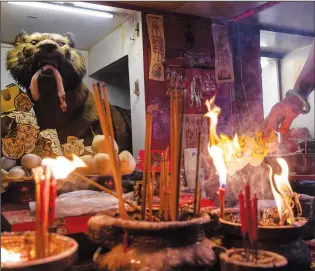  ?? ?? A practition­er burns a paper with the image of a tiger March 6 during a “villain hitting” ceremony on the day of “ging zat.”