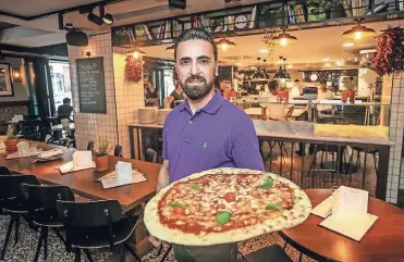  ?? RP-FOTO: HANS-JÜRGEN BAUER ?? Betriebsle­iter Dara Baban serviert im Restaurant L’Osteria Riesenpizz­en.