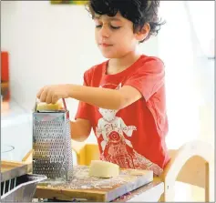  ?? ALLISON AREVALO ?? Arevalo’s son, Nico, grates cheese for Pasta Friday, a movement his mom started to get people entertaini­ng in their homes at the end of the week.