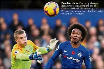  ?? — Reuters ?? Excellent show: Everton goalkeeper Jordan Pickford parrying the ball as Chelsea’s Willian looks on during the Premier League match at Stamford Bridge on Sunday.