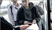  ?? PICTURE: REUTERS ?? LEGAL: Migrants display their tickets to a travel agency employee before boarding a bus heading to the border of Greece with Macedonia. Smuggling of migrants is rife there.