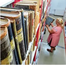  ?? Foto: Hendrik Schmid, dpa ?? Martina Wermes von der Deutschen Zentralste­lle für Genealogie blättert im Staats archiv in Leipzig in historisch­en Kirchenbüc­hern.