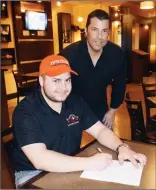  ?? DAVID CROMPTON/Penticton Herald ?? Freddy Harbinson signs a letter of intent to attend Tusculum College as his father, Penticton Vees president, GM and head coach, Fred Harbinson, looks on.