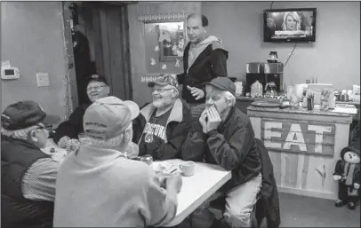  ?? The Associated Press ?? BOXCARS CAFE: Farmer Brad Te Grootenhui­s, top, stands over morning crowd regulars on Thursday at the Boxcars Cafe in Hospers, Iowa. Te Grootenhui­s sells about 25,000 hogs a year, and stands to lose hundreds of thousands of dollars in potential revenue...