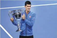  ?? — AFP ?? LONDON: Serbia’s Novak Djokovic holds the trophy of the ATP World No 1 Award after it was presented to him following his men’s singles group stage match against Japan’s Kei Nishikori on day one of the ATP World Tour Finals tennis tournament in London...