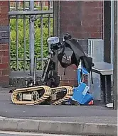  ?? ?? ● The bomb disposal robot gets to grips with the device