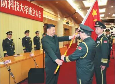  ?? LI GANG / XINHUA ?? President Xi Jinping presents the PLA flag to Major General Deng Xiaogang, president of the National University of Defense Technology, at a ceremony on Wednesday in the Central Military Commission headquarte­rs building in Beijing.