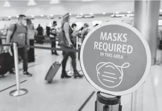  ?? Joe Raedle / Getty Images ?? Signs remind travelers to wear masks at Miami Internatio­nal Airport last month. An executive order signed by President Joe Biden mandates mask-wearing on airplanes and in airports.