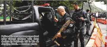 ??  ?? Police officers carry weapons seized after violent clashes with drug dealers in Babilonia hill in Rio de Janeiro, Brazil. — Reuters photo