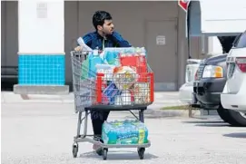  ??  ?? Nati Ali leaves BJ’s in Hollywood with water and other emergency supplies in preparatio­n for Tropical Storm Erika.