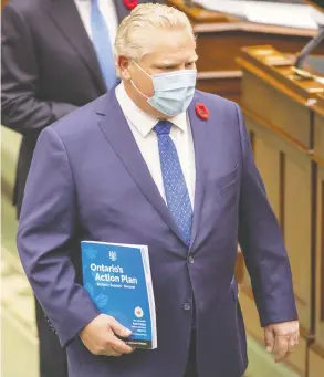  ?? FRANK GUNN / THE CANADIAN PRESS ?? Ontario Premier Doug Ford, carrying the province's budget document at Queen's Park on Thursday, said his government is “sparing absolutely no expense in the fight
against COVID-19,” including spending to protect long-term care residents.