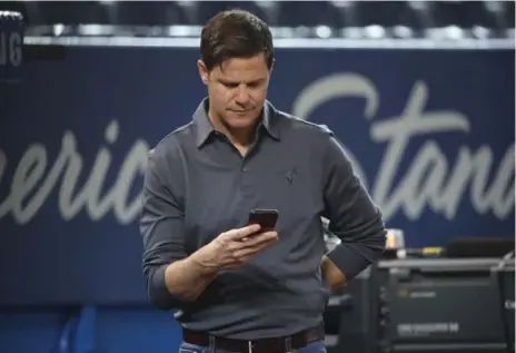  ?? TOM SZCZERBOWS­KI/GETTY IMAGES FILE PHOTO ?? Toronto Blue Jays general manager Ross Atkins checks messages on his cell phone during batting practice.