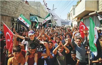  ?? AFP ?? Residents wave flags of the opposition and of Turkey during a demonstrat­ion against the Syrian regime in the rebel-held town of Hazzanu, about 20 km northwest of Idlib city, on Friday.