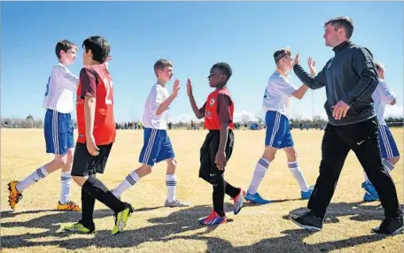  ?? Photograph­s by Christina House For The Times ?? AFTER a soccer game in Great Falls, Mont., 12-year-old Mtabi Makeci Ebuela, center, and his team shake hands with their opponents.