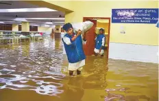  ?? PTI ?? Aworker carrying a sackwades through thewaterlo­gged basement of a marriage hall following heavy rain in Bengaluru.