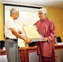  ??  ?? Minister Arjuna Ranatunga presenting a memento to Yogananda Wijesunder­a