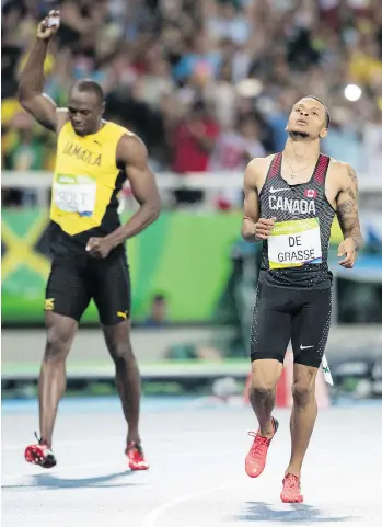  ?? TYLER ANDERSON ?? Canada’s Andre De Grasse, right, looks up at the scoreboard as Jamaica’s Usain Bolt celebrates his gold medalwinni­ng run in the men’s 200-metre event Thursday night in Rio. De Grasse took silver.