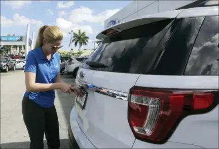  ?? THE ASSOCIATED PRESS ?? Ford sales consultant Yanaisis Milian removes the dealer tag on a sold 2017 Ford Explorer at an auto dealership in Hialeah, Fla. Automakers reported financial results Monday.