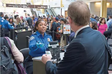  ??  ?? Una empleada de la TSA inspeccion­a documentos de los pasajeros en el aeropuerto Ronald Reagan