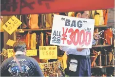  ??  ?? A shop employee holds a placard to attract customers in Tokyo. Japan’s economy slid into reverse for the first time in two years at the beginning of the year, hit by sluggish consumptio­n and a winter cold snap, but analysts predicted the world’s...