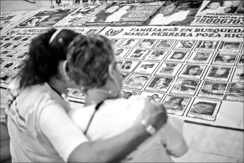  ?? — AFP photos ?? Herrera (right) looks at portraits during a mass as part of the activities of the fourth National Search Brigade, in Huitzuco de los Figueroa, Guerrero state, Mexico.