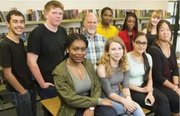  ?? CARLOS OSORIO/TORONTO STAR ?? Teacher-librarian Wayne Parker, centre, says circulatio­n is down at the library in Brampton’s North Park Secondary school. He and his students attribute that change to the amount of time kids spend online in front of screens.