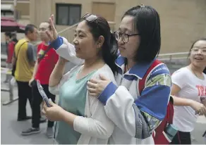  ?? PHOTOS: GREG BAKER/AFP/GETTY IMAGES ?? Above: A student waves to her friends as she prepares to leave with her mother after she finished a college entrance exam at a school in Beijing. Some students are reportedly hiring people to pose as their parents to attend parent-teacher meetings....