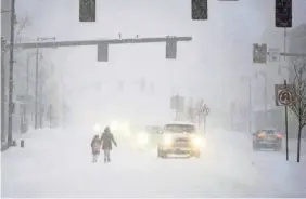  ?? BEN GARVER/AP ?? Pedestrian­s walk along North Street in Pittsfield, Mass, early Thursday as a nor'easter pummels the Berkshires.