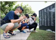  ?? (AP/Kyodo News) ?? A family prays Tuesday in front of a monument at Peace Memorial Park in Itoman on the island of Okinawa. The monument lists the names of civilians and service members of all nationalit­ies who died in the Battle of Okinawa during World War II.