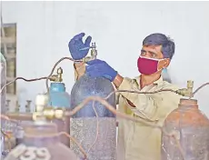  ?? — AFP photo ?? A worker fills medical oxygen cylinders for hospital use on Covid-19 patients at a plant in Allahabad.