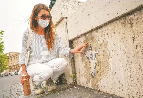  ?? (AP/Andrew Medichini) ?? Artist Alessia Babrow shows her street art. One night in early 2019, the Rome street artist glued a stylized image of Christ she made to a bridge near the Vatican. A year later, she was shocked to learn the Vatican used her image, featuring her hallmark heart emblazoned across Christ’s chest, as its 2020 Easter postage stamp.