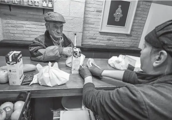  ??  ?? Una voluntaria del París 365 reparte un lote de comida a un usuario.