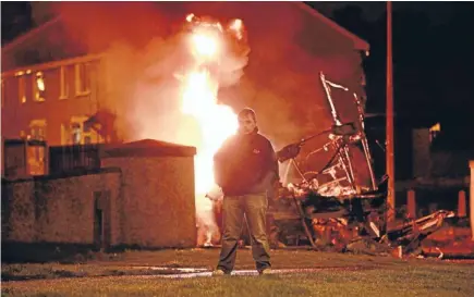  ?? Photo: Reuters ?? Burning anger: A man stands in front of the wreckage of a double-decker bus that was hijacked and set alight by loyalists in the Rathcoole Estate, Belfast.
