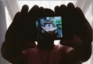  ?? Wilfredo Lee / Associated Press ?? A Cuban migrant, who wished not to be identified for fear of reprisals against his family back on the island nation, holds up a picture of a home-made boat that brought him and three others to the U.S. on June 21 in North Miami Beach, Fla.