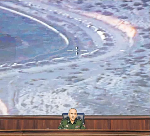  ??  ?? Above, Lieutenant General Sergei Rudskoy of the general staff of the Russian armed forces speaks during a briefing about the country’s attacks on Isil oil convoys, and, left, footage released by Moscow of trucks that were alleged to be transporti­ng...