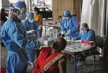  ?? Manish Swarup / Associated Press ?? Health workers conduct COVID-19 antigen tests in New Delhi. In June, India began using the cheaper, faster but less accurate tests for the coronaviru­s — a strategy the U.S. is considerin­g.