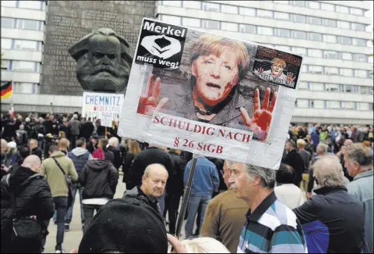  ?? Jens Meyer The Associated Press ?? A protester holds a poster Saturday with a photo of Chancellor Angela Merkel reading “Merkel must go” and alleging she is guilty of incitement in Chemnitz, eastern Germany.