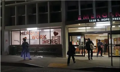  ?? Photograph: Damian Dovarganes/AP ?? Healthcare workers walk in for the night shift at the emergency entrance of the California Hospital Medical Center in downtown Los Angeles, in February 2022.