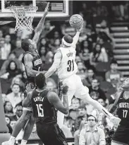  ?? Mark Mulligan / Staff photograph­er ?? The Rockets’ Gary Clark, left, challenges a drive by Trail Blazers guard Seth Curry.