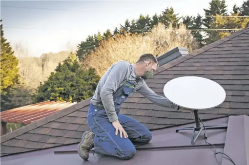  ?? PHOTOS BY LUKE CHRISTOPHE­R FOR FOOTHILLS FORUM ?? Bjoern Jemsby positions a Starlink satellite dish on the roof of his home in Castleton.